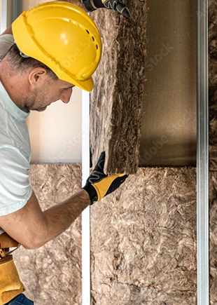 Handwerker verlegt Dämmung in einer Trockenbauwand