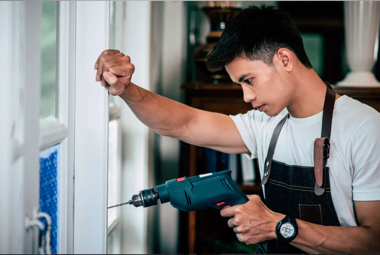 Handwerker beim Bohren am Fensterrahmen